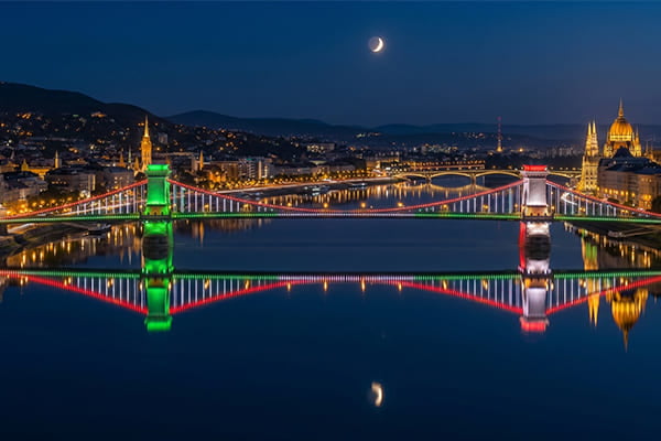 A bridge's colorful lights reflecting perfectly in calm water